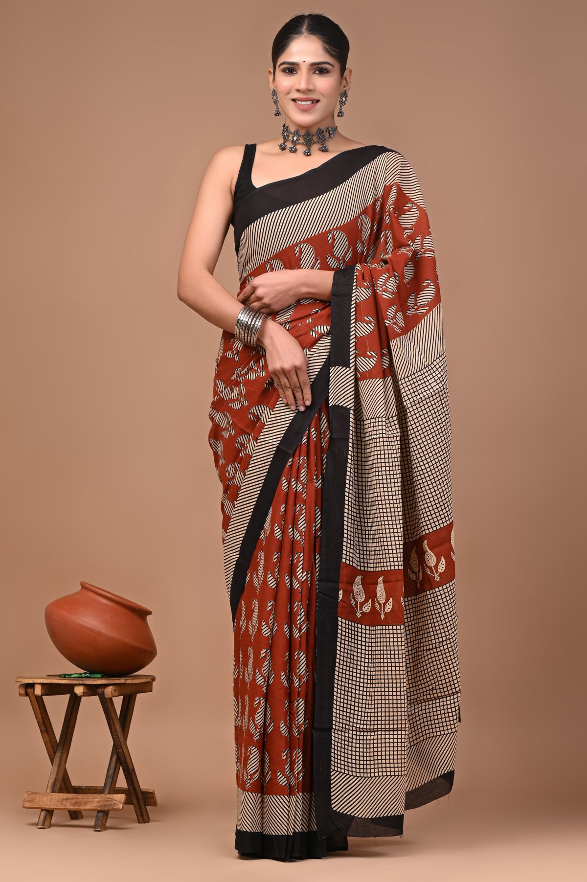 Woman wearing a traditional mul cotton saree with a brown background