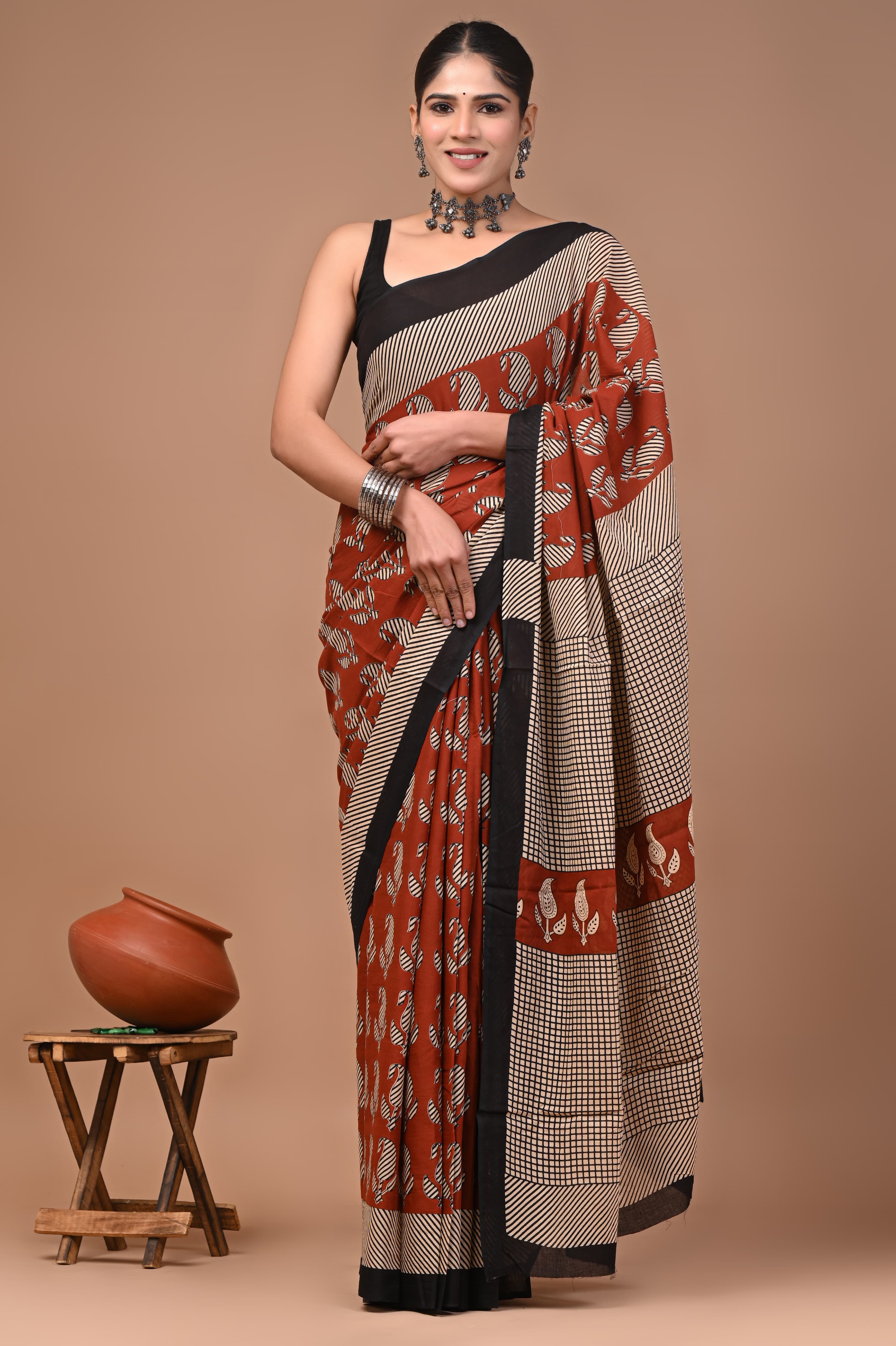 Woman wearing a traditional mul cotton saree with a brown background
