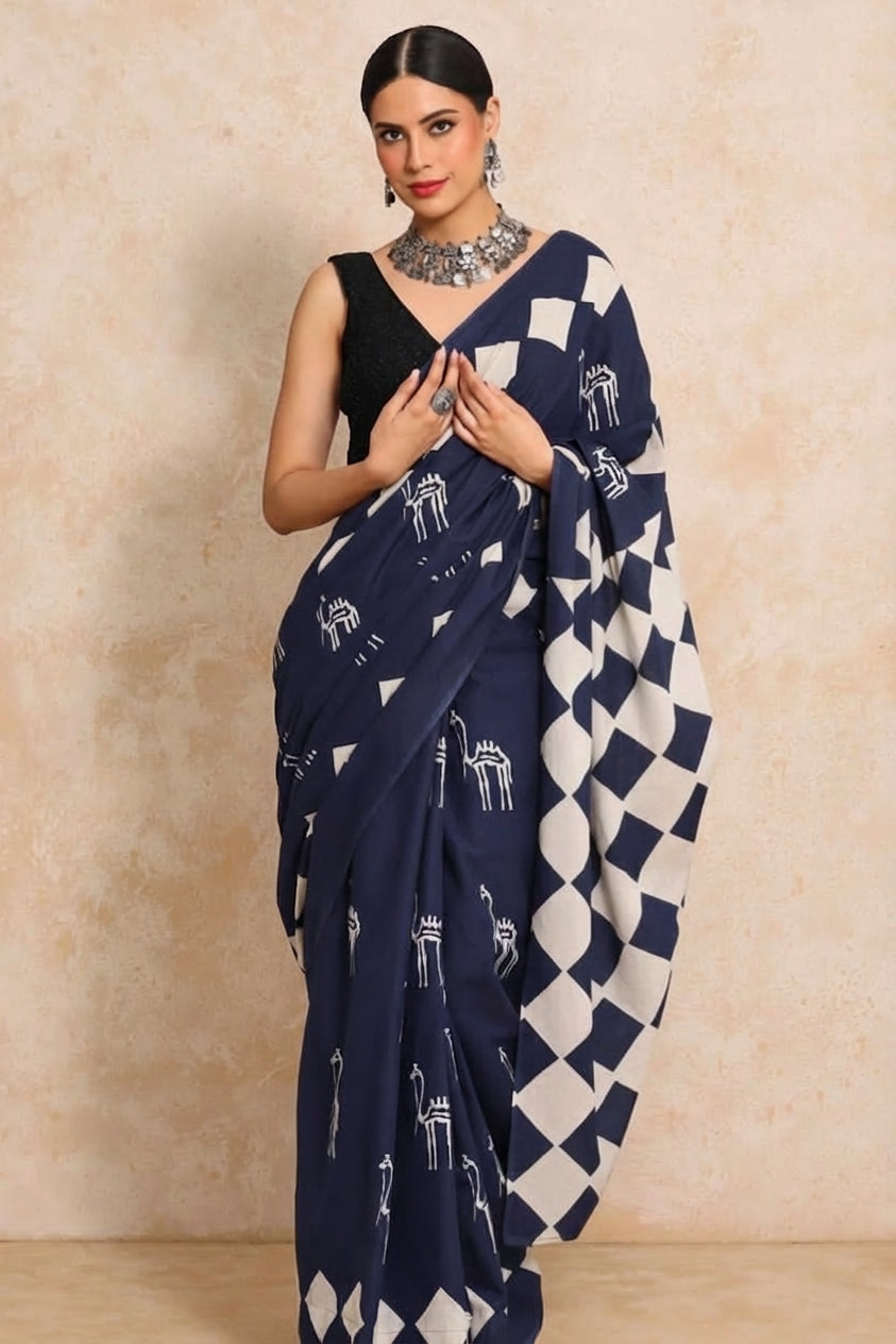 Woman wearing a navy blue and white nul cotton saree with a beige background