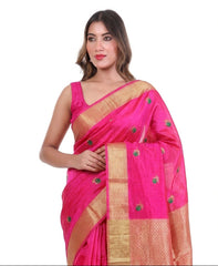 Woman wearing a pink saree with gold border, surrounded by fabric samples.